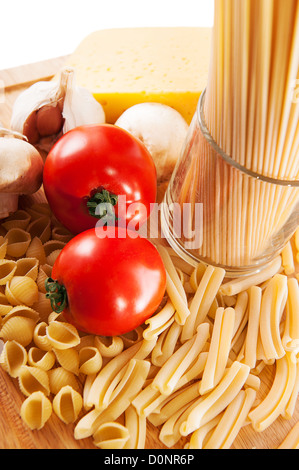Different types of pasta and vegetables on wooden board