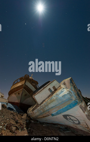 Abandoned derelict wooden boats in the desert under a night sky with abstract lighting effects Stock Photo