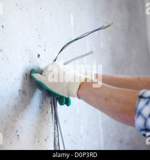 worker puts the wires in the wall Stock Photo
