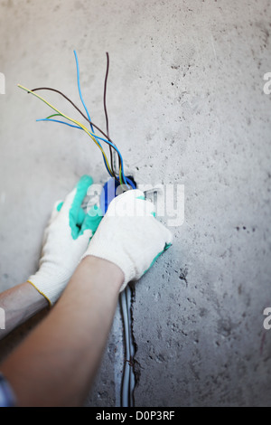 worker puts the wires in the wall Stock Photo