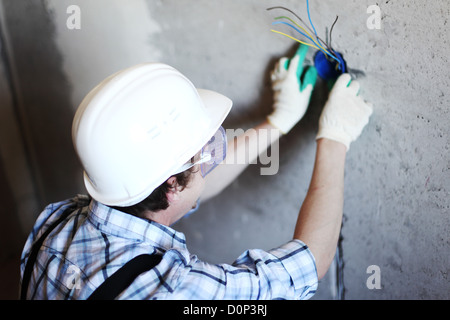 worker puts the wires in the wall Stock Photo