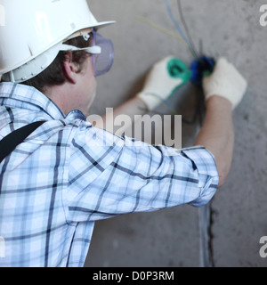 worker puts the wires in the wall Stock Photo