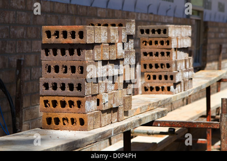 Clay bricks are stacked on scaffolding at a new home under construction site waiting for the bricklayer to install. Stock Photo