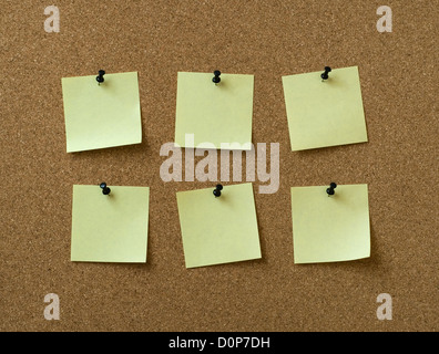 six yellow notes pinned to cork background Stock Photo