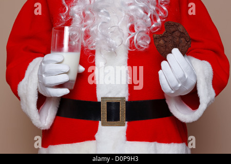 Santa Claus holding a glass of milk and a chocolate cookie. Stock Photo