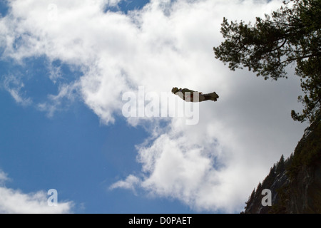 This BASE jumper is proximity tracking down the valley after he exiting from a cliff. He dives with high speed and has a rush! Stock Photo