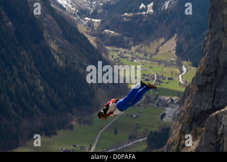 This BASE jumper is proximity tracking down the valley after he exiting from a cliff. He dives with high speed and has a rush! Stock Photo