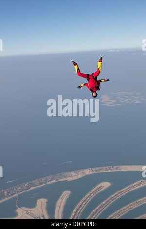 Skydiver girl is flying free over the Dubai palm and performance a head down move. The scenery is perfect from this hight. Stock Photo