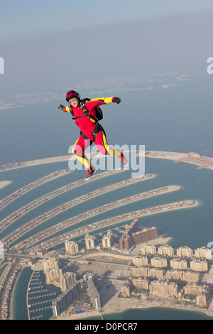 Skydiver girl is flying free over the Dubai palm and performance a free style move. The scenery is perfect from this hight. Stock Photo