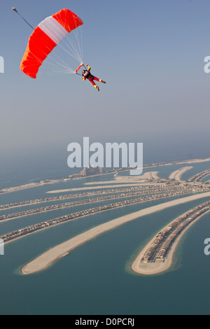 Skydiver under canopy is flying high in the sky over the Dubai Palm facing the Atlantis Hotel. Stock Photo