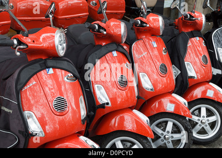 Paris, France: Red Piaggio Vespa motor scooters for hire - parked in a row outside a rental shop. Stock Photo