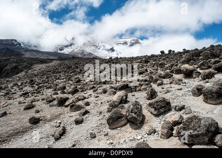 MOUNT KILIMANJARO, Tanzania — The rocky, rugged apline desert on Mt Kilimanjaro Lemosho Route. These shots were taken on the trail between Moir Hut Camp and Lava Tower at approximately 14,500 feet. In the distance is the summit, partly hidden by clouds. Stock Photo