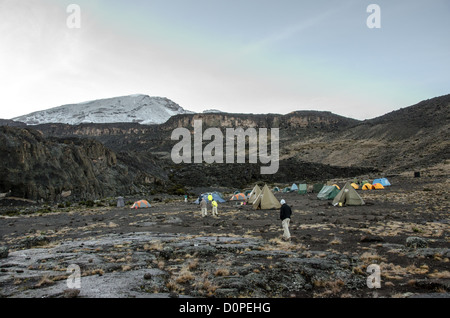 MT KILIMANJARO, Tanzania - Tents at Moir Hut Camp (13,660 feet) on Mt Kilimanjaro's Lemosho Route. The mountain peak, covered in snow, is in the distance at left. Stock Photo