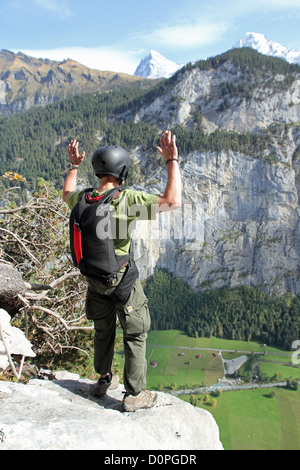 BASE jumper is diving from a cliff down into the valley. He is doing the frog position to be save exiting. Stock Photo