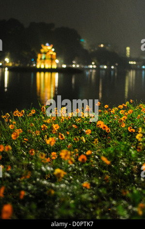 HANOI, Vietnam — Turtle Tower (also known as Tortoise Tower on a small island in Hoan Kiem Lake in the historical center of Hanoi, Vietnam. In the foreground is a garden of bright flowers. Stock Photo