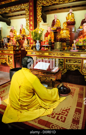 HANOI, Vietnam — A Buddhist monk performs prayers at the altar inside Tran Quoc Pagoda, located on West Lake (Ho Tay). Originally constructed in the 6th century on the Red River's banks, this ancient temple was relocated to Kim Ngu islet in 1615. The pagoda stands as one of Vietnam's oldest Buddhist temples and continues to serve as an active place of worship. Stock Photo