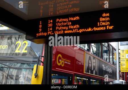 London, England, UK. Bus stop. Red double-decker and electronic sign giving bus times Stock Photo