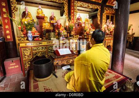 HANOI, Vietnam — A Buddhist monk performs prayers at the altar inside Tran Quoc Pagoda, located on West Lake (Ho Tay). Originally constructed in the 6th century on the Red River's banks, this ancient temple was relocated to Kim Ngu islet in 1615. The pagoda stands as one of Vietnam's oldest Buddhist temples and continues to serve as an active place of worship. Stock Photo