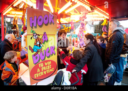 Parents and children playing Hook a duck, the Christmas fair fairground, Bury St Edmunds Suffolk UK Stock Photo