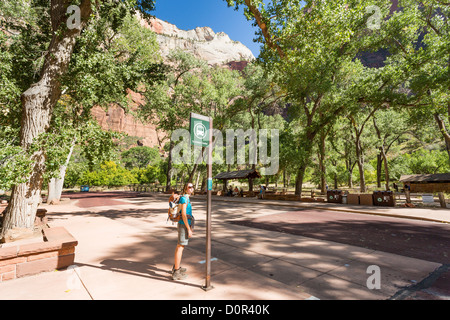 Young woman hiker reading shuttle schedule at the bus stop in Zion National Park Stock Photo