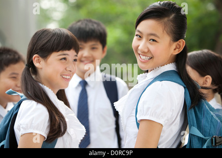 Happy schoolgirl in uniform with her friends outdoors Stock Photo