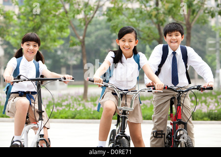Happy schoolchildren in uniform with bicycles outdoors Stock Photo