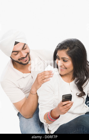 Woman using a mobile phone with her husband sitting beside her Stock Photo