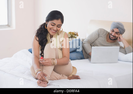 Woman painting toenails while her husband working on a laptop Stock Photo