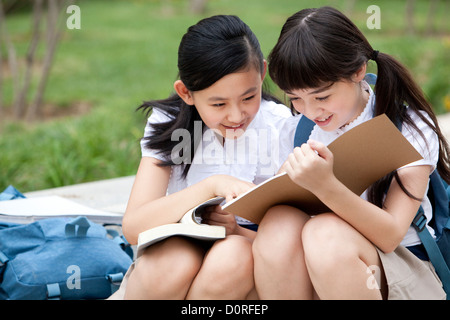 Lovely schoolgirls reading books together outdoors Stock Photo
