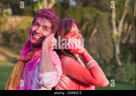 Couple in Holi colors talking on mobile phones Stock Photo