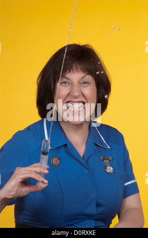 Portrait of a nurse baring her teeth and squirting a syringe. Stock Photo