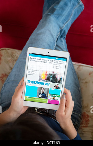 Woman using Kindle application of read digital edition of The  Observer newspaper  on an iPad mini tablet computer Stock Photo