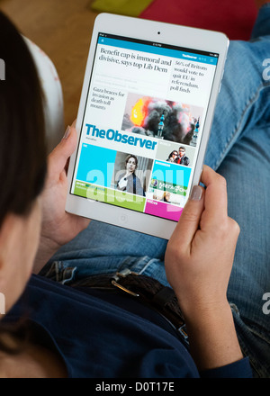 Woman using Kindle application of read digital edition of The  Observer newspaper  on an iPad mini tablet computer Stock Photo