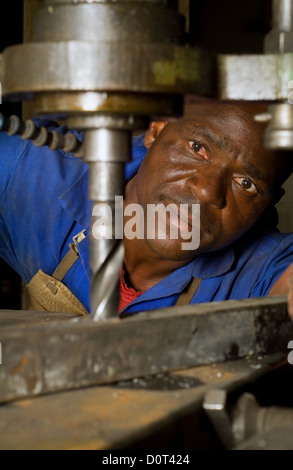 South African or American worker engineer working with industrial drill press Stock Photo