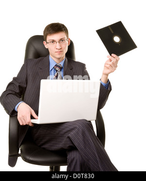 Young man with laptop and floppy disk sitting in chair Stock Photo