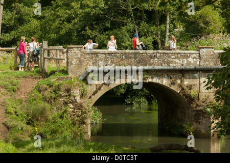 peole on old small stone bridge over the River Rother Outside Cowdray Ruins Stock Photo