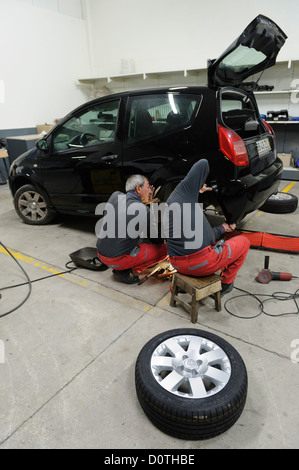 Mechanics changing car tyre in auto garage Stock Photo