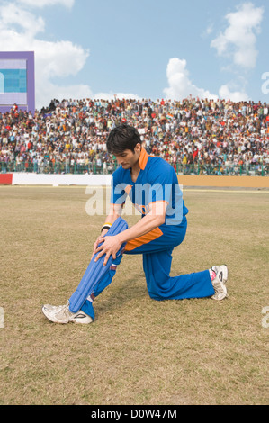 Cricket player adjusting his shin guard Stock Photo