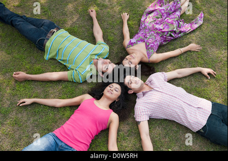 Friends lying in a huddle in a lawn Stock Photo