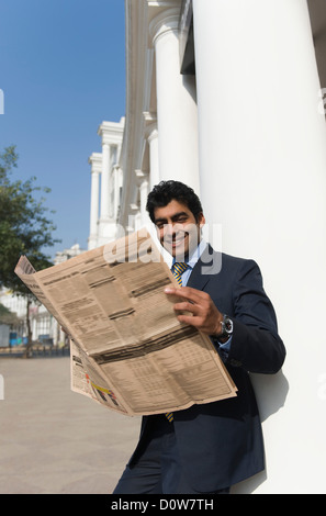 Businessman reading a newspaper, Gurgaon, Haryana, India Stock Photo