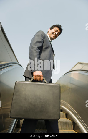 Businessman standing on an escalator, Gurgaon, Haryana, India Stock Photo