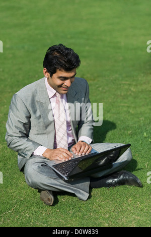 Businessman working on a laptop in a park, Gurgaon, Haryana, India Stock Photo