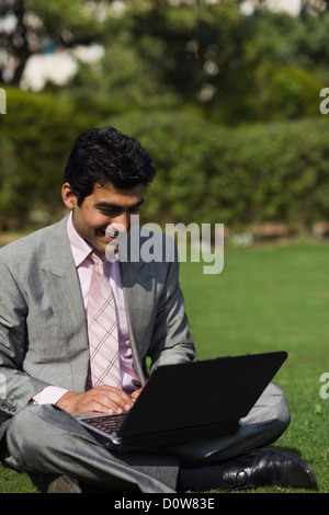 Businessman working on a laptop in a park, Gurgaon, Haryana, India Stock Photo