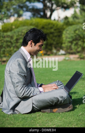 Businessman working on a laptop in a park, Gurgaon, Haryana, India Stock Photo
