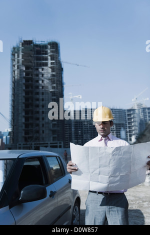 Architect looking at a blueprint at a construction site, Gurgaon, Haryana, India Stock Photo