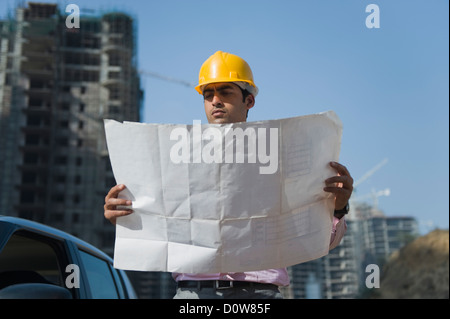 Architect looking at a blueprint at a construction site, Gurgaon, Haryana, India Stock Photo
