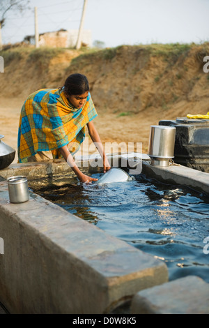 Girl cleaning pots in a tube well reservoir, Farrukh Nagar, Gurgaon, Haryana, India Stock Photo