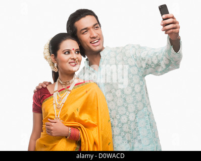 Couple taking a picture of themselves in traditional clothing with a mobile phone Stock Photo