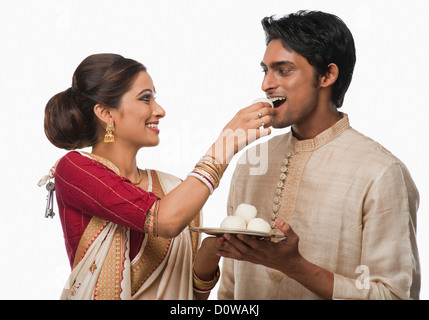 Bengali woman feeding a rasgulla to a man Stock Photo