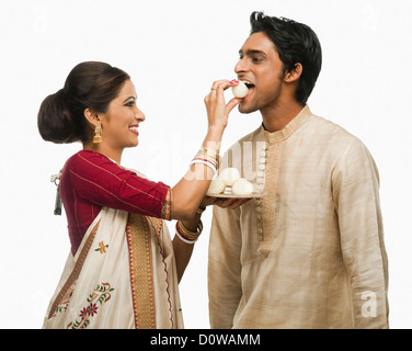 Bengali woman feeding a rasgulla to a man Stock Photo